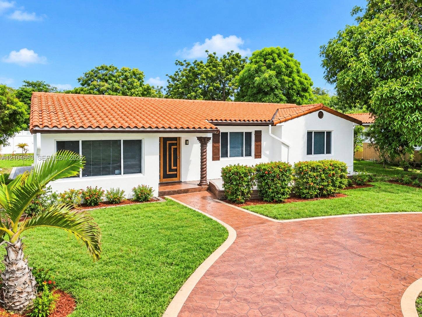 305 NW 111th Street, Miami Shores, FL 33168 Single-story exterior featuring a terracotta tile roof, white stucco facade, decorative spiral support column, and a stamped concrete driveway