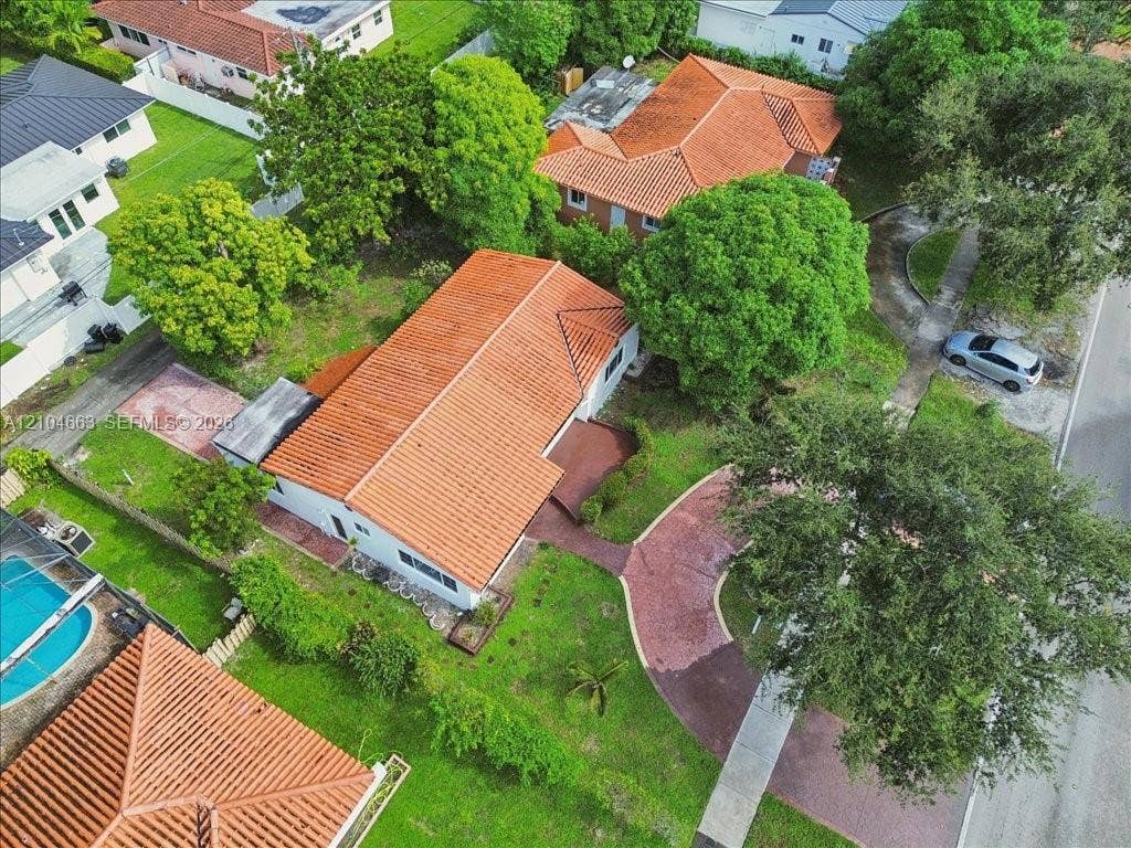 305 NW 111th Street, Miami Shores, FL 33168 Aerial perspective of a residence featuring a terracotta-tile roof, paved circular driveway, and established canopy trees across the landscaped grounds
