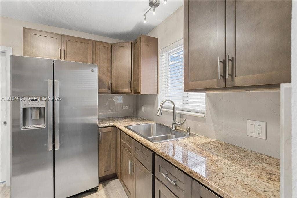 305 NW 111th Street, Miami Shores, FL 33168 Kitchen featuring shaker-style cabinetry, stone countertops, stainless steel side-by-side refrigerator, stainless steel dual-basin sink with a gooseneck faucet, and track lighting