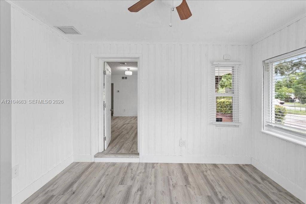 305 NW 111th Street, Miami Shores, FL 33168 Room interior featuring wood-finish flooring, vertical panel wall detailing, and a ceiling fan