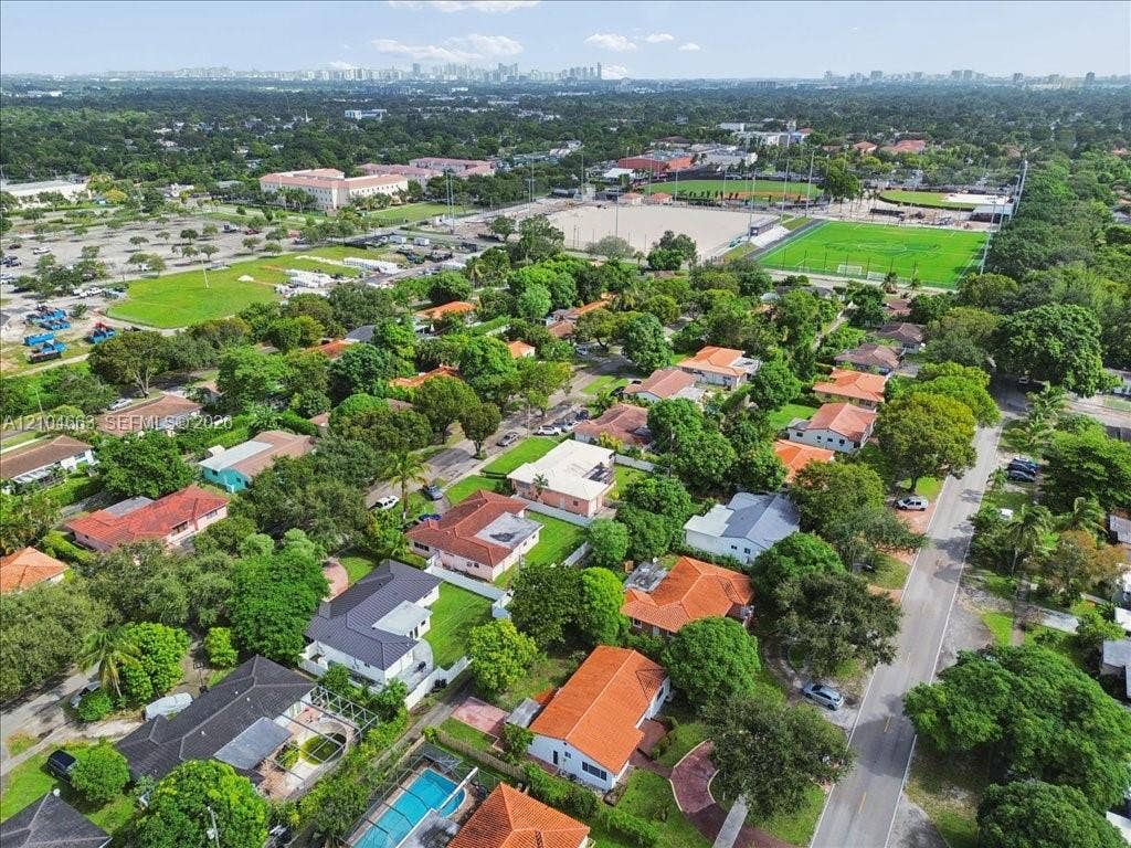 305 NW 111th Street, Miami Shores, FL 33168 Aerial perspective of a residential neighborhood featuring mature canopy trees, tiled roofing, green space, and hardscape pathways