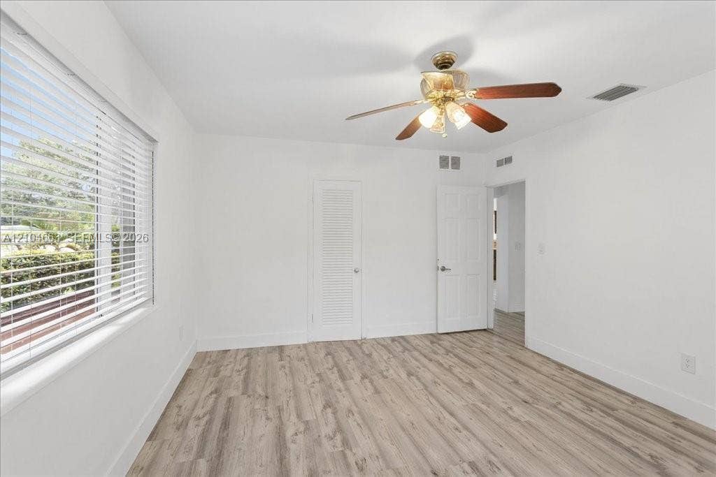 305 NW 111th Street, Miami Shores, FL 33168 Interior room featuring wood-finish flooring, a multi-blade ceiling fan with integrated lighting, horizontal window blinds, and louvered closet doors