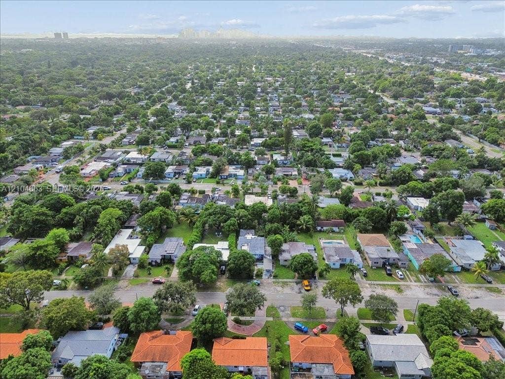 305 NW 111th Street, Miami Shores, FL 33168 Aerial perspective of a residential neighborhood featuring mature tree canopy and city skyline backdrop