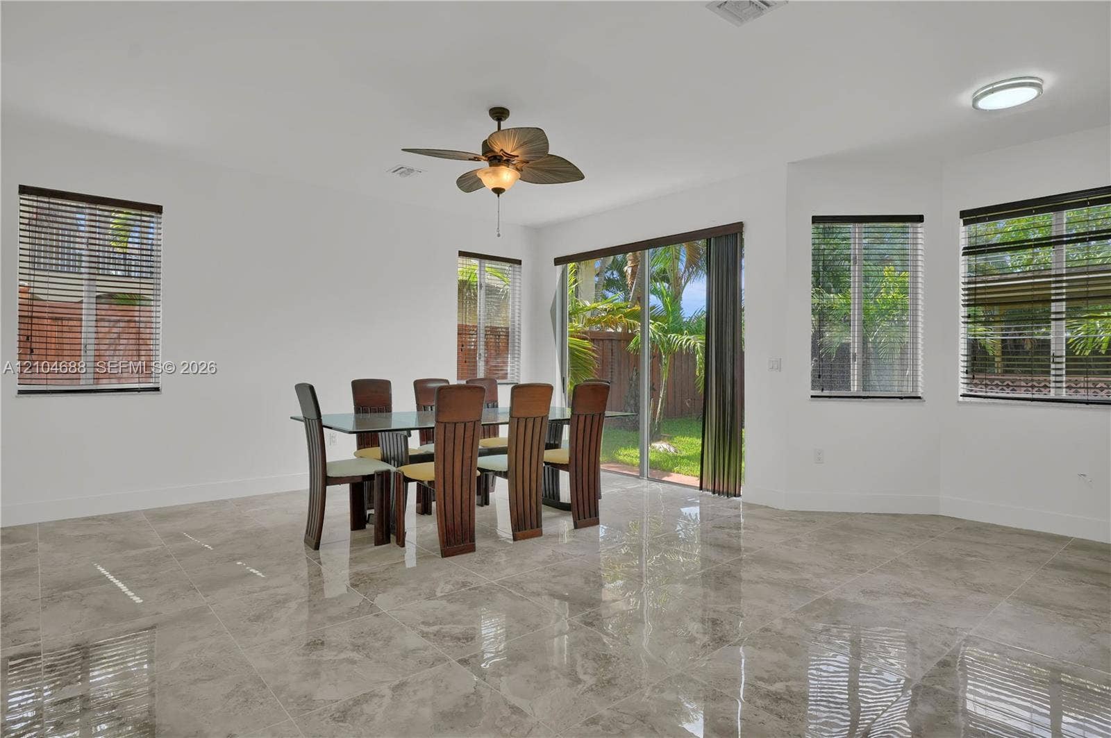 Neutral-toned tile flooring, oversized sliding glass door, recessed lighting, and a ceiling fan with integrated light fixture