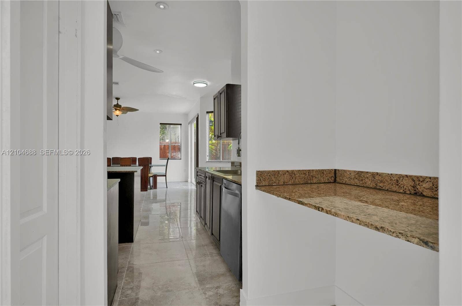 Kitchen featuring dark cabinetry, stone-surface counters, high-gloss tile flooring, and integrated ceiling lighting