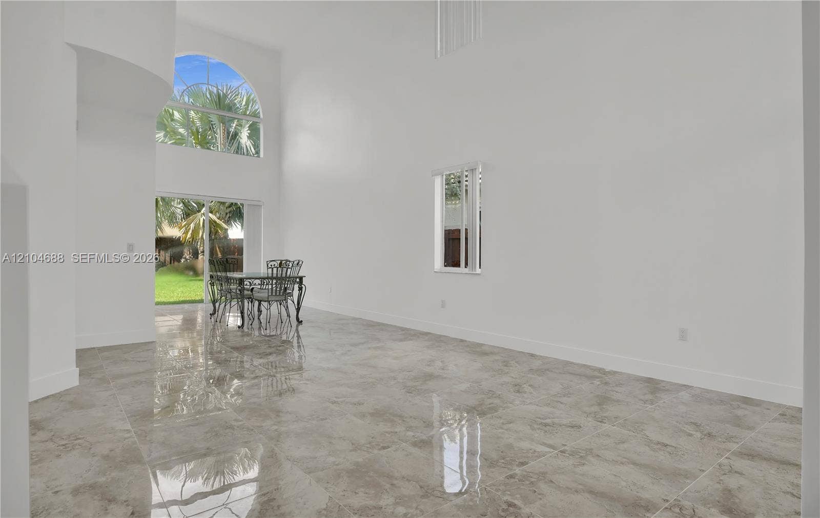 Double-height ceiling, large-format tile flooring, arched clerestory window, and sliding glass door