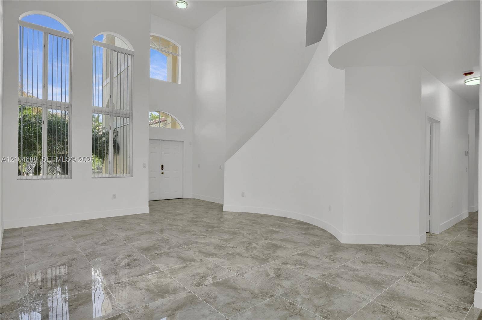 Double-height foyer featuring stone-finish floor tiling, arched windows, and a curved architectural wall