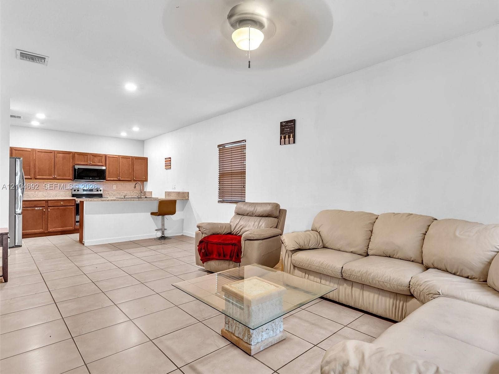 714 SE 37th Place, Homestead, FL 33033 Open-concept interior featuring large-format tile flooring, wood cabinetry, stone countertops, a breakfast bar, and recessed lighting