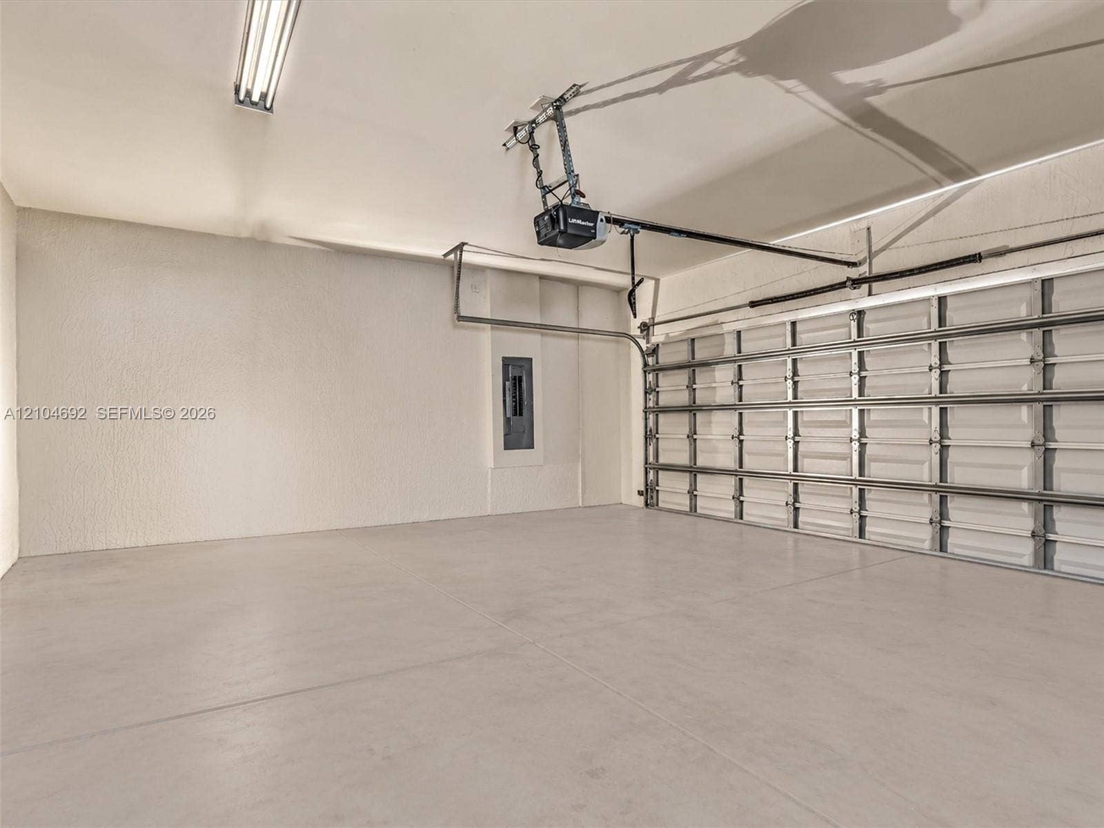 714 SE 37th Place, Homestead, FL 33033 Finished garage interior featuring concrete flooring, textured walls, a multi-panel overhead door, and an integrated electrical service panel