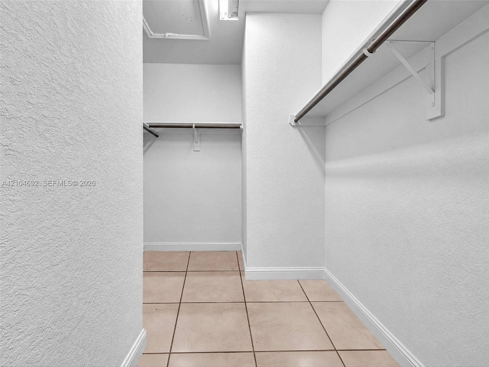 714 SE 37th Place, Homestead, FL 33033 Walk-in closet featuring ceramic tile flooring, neutral textured wall finishes, and integrated shelving with metal hanging rods