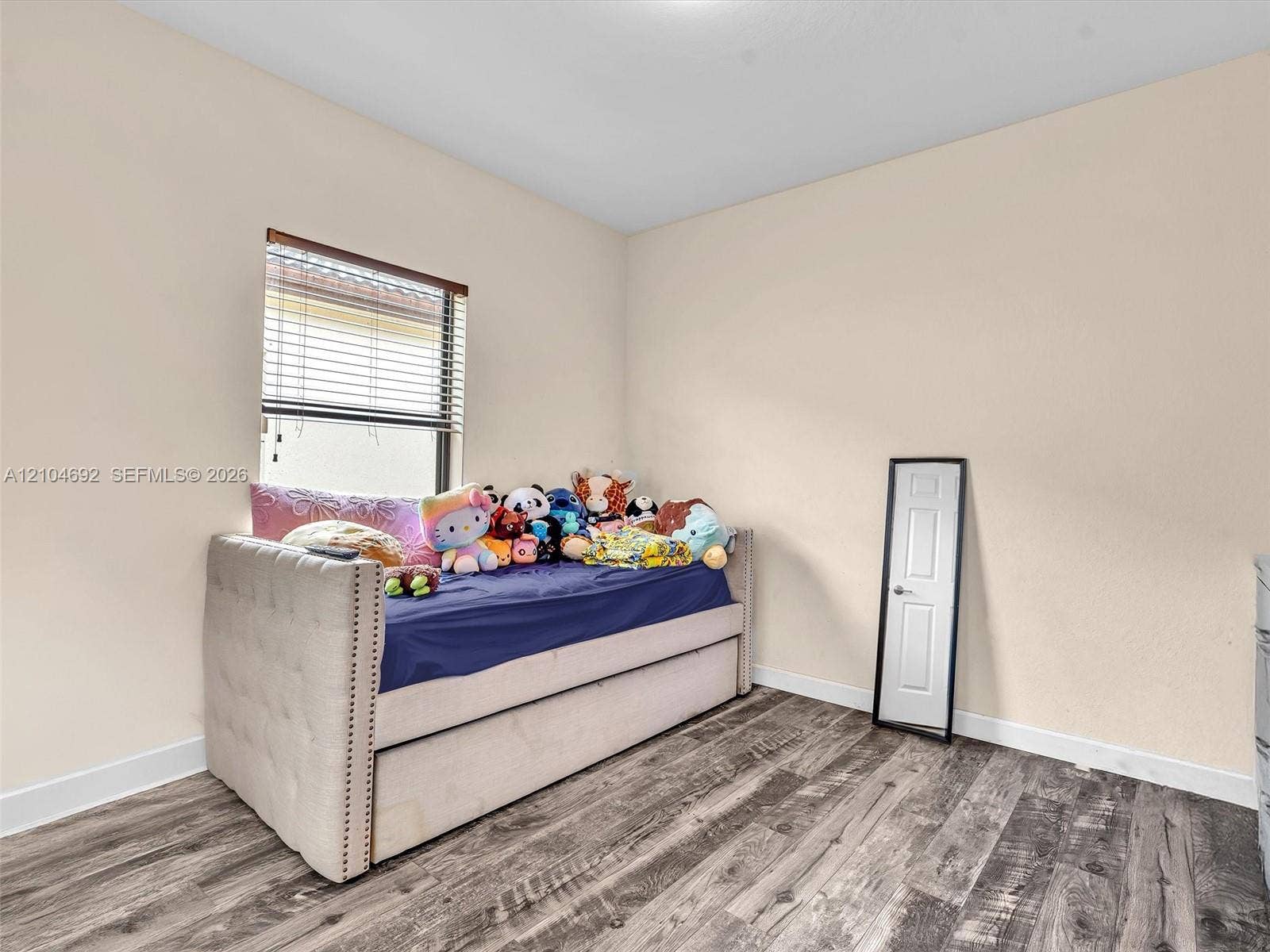 714 SE 37th Place, Homestead, FL 33033 Room interior featuring wood-finish flooring, neutral wall paint, and a window with horizontal blinds