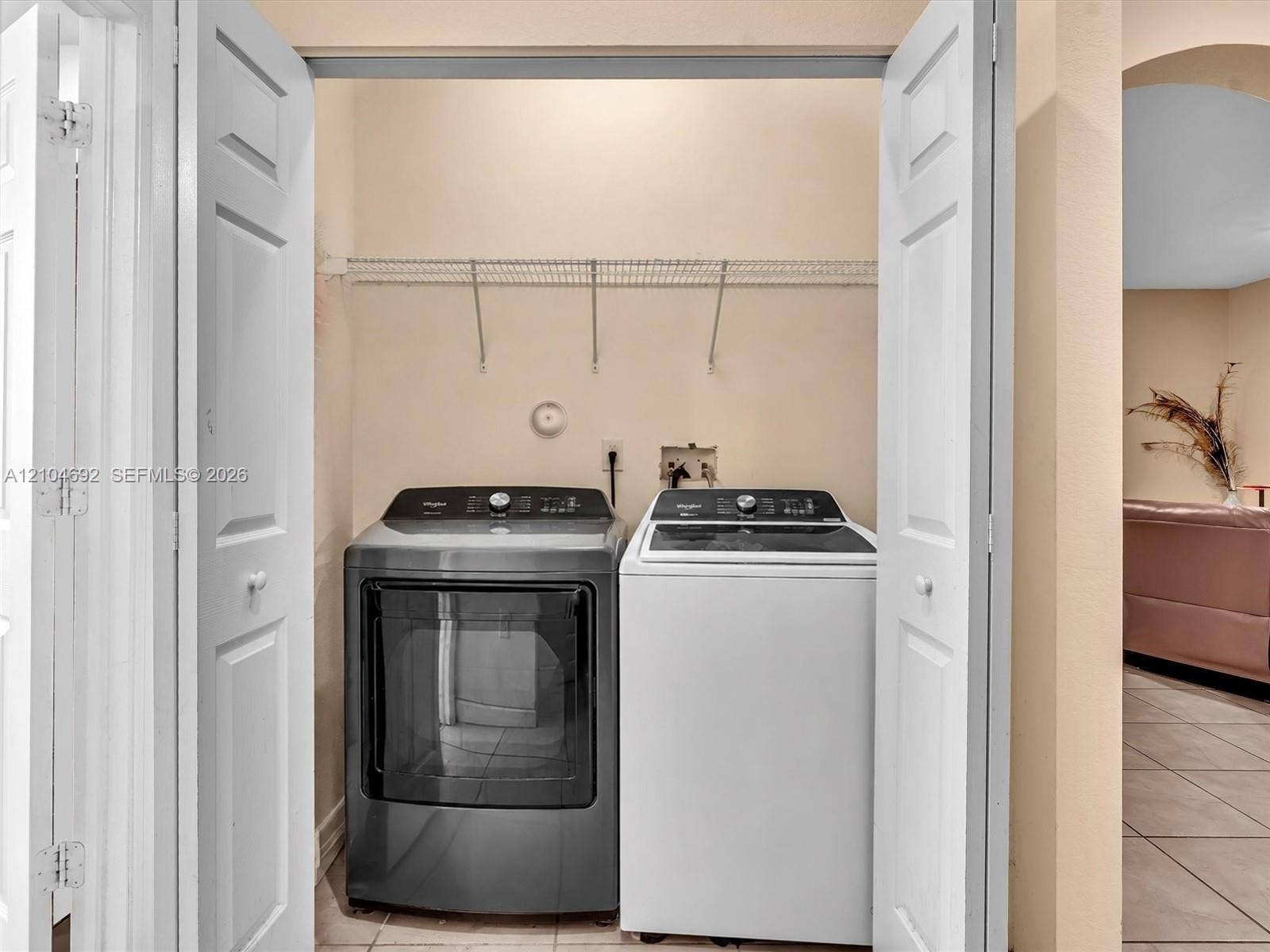 714 SE 37th Place, Homestead, FL 33033 Laundry area featuring bi-fold doors, white ceramic tile flooring, and integrated wire shelving