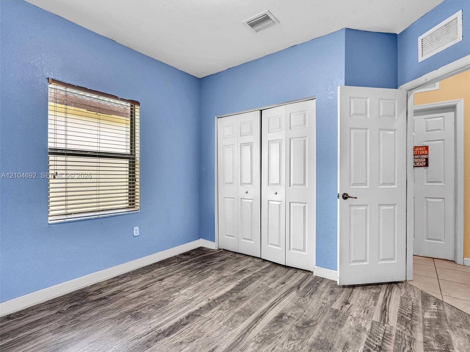 714 SE 37th Place, Homestead, FL 33033 Room featuring wood-finish flooring, two-panel interior doors, and a double-door closet