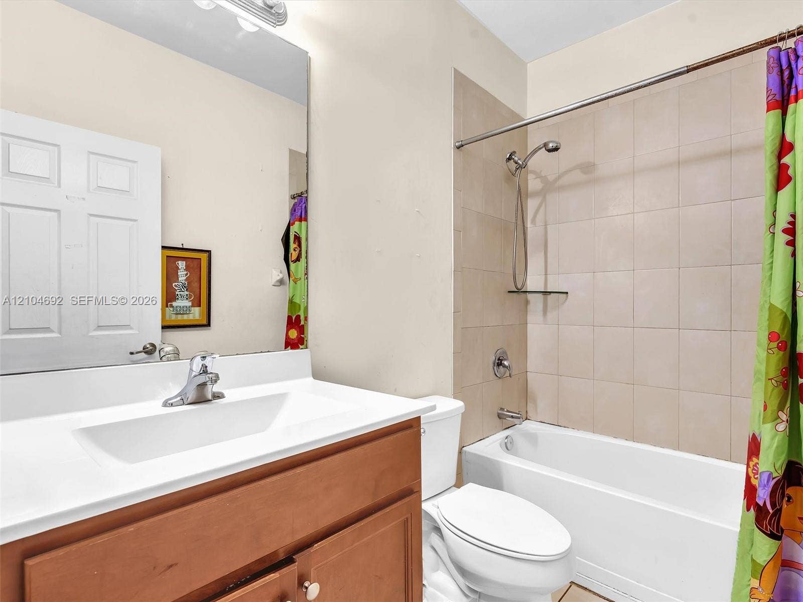 714 SE 37th Place, Homestead, FL 33033 Bathroom featuring a wood-finish vanity with a white countertop, large wall-mounted mirror, and a tile-surround shower and tub combination with a detachable showerhead