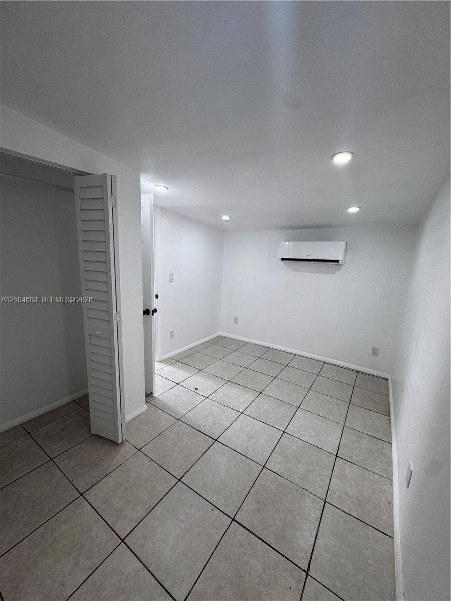 Recessed lighting, tile flooring, louvered bi-fold closet doors, wall-mounted air conditioning unit