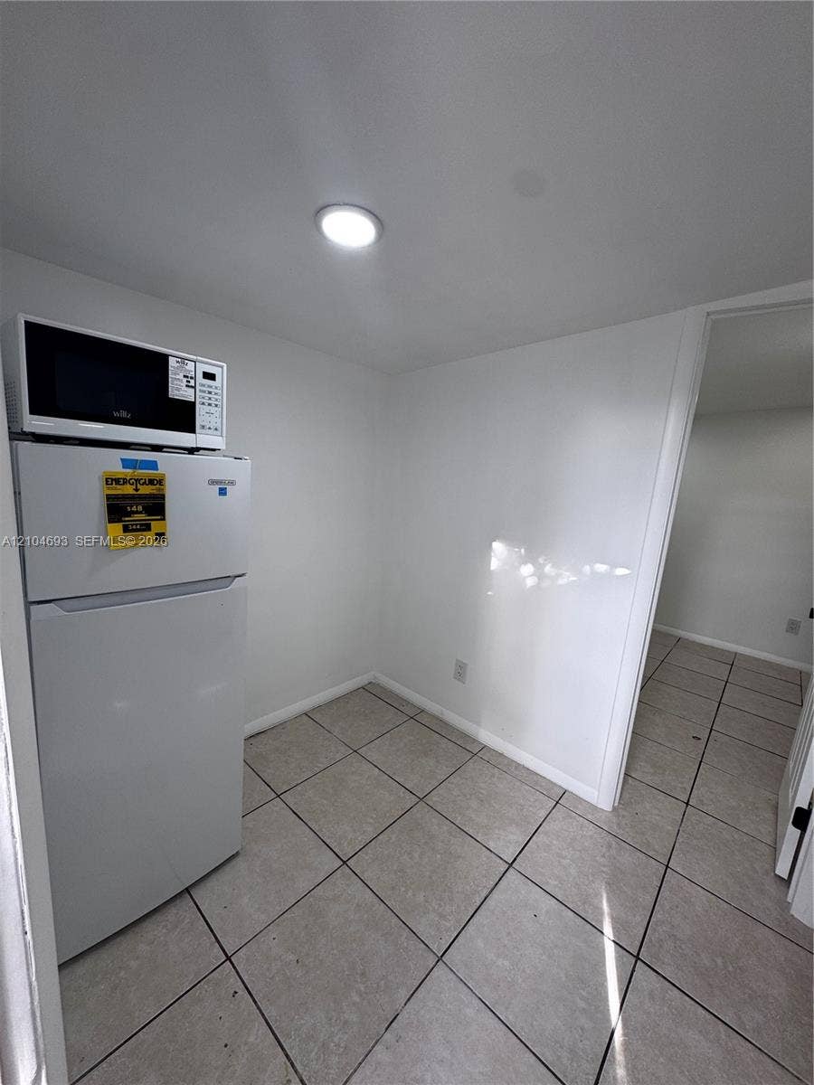 Recessed ceiling lighting illuminates the space, featuring white walls and square tile flooring