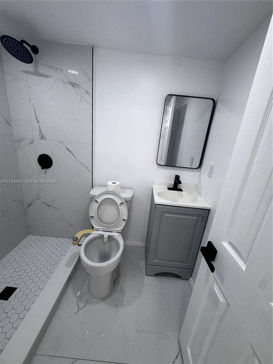 Walk-in shower with hexagonal mosaic tile floor and large format wall tile, complemented by a single vanity with storage, and a rectangular mirror