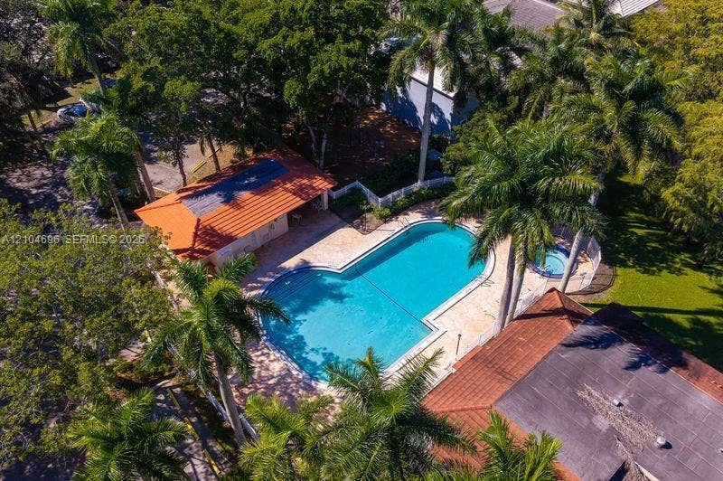 9963 NW 2nd Court, Plantation, FL 33324 Swimming pool with integrated spa, stone-finish deck, and covered pavilion, surrounded by mature palm trees