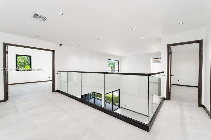 9963 NW 2nd Court, Plantation, FL 33324 Open-concept landing featuring glass railings with dark metal trim, large-format tile flooring, and recessed ceiling lighting