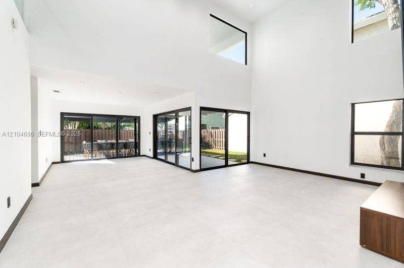 9963 NW 2nd Court, Plantation, FL 33324 Double-height ceilings, large-format tile flooring, recessed lighting, and expansive glass sliding doors with black frames