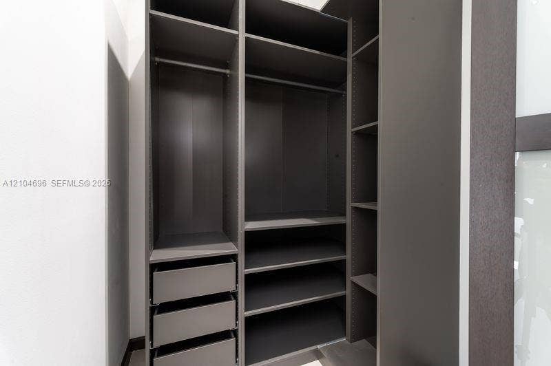 9963 NW 2nd Court, Plantation, FL 33324 Custom storage system featuring dark wood-finish cabinetry, integrated shelving, tiered drawer units, and metal garment rods