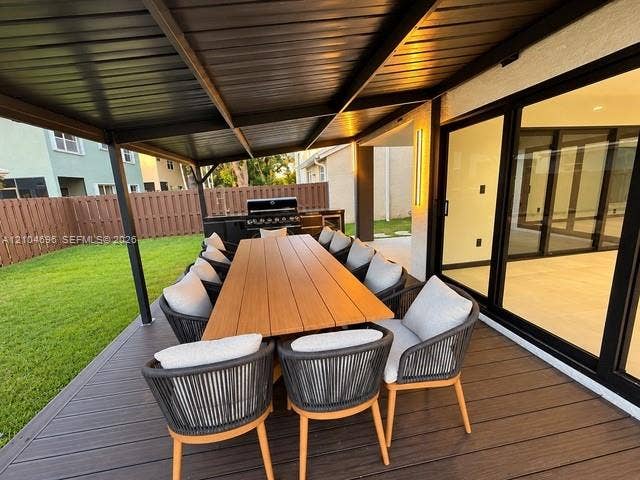 9963 NW 2nd Court, Plantation, FL 33324 Covered patio featuring composite decking, built-in outdoor kitchen with grill, and large-format sliding glass doors