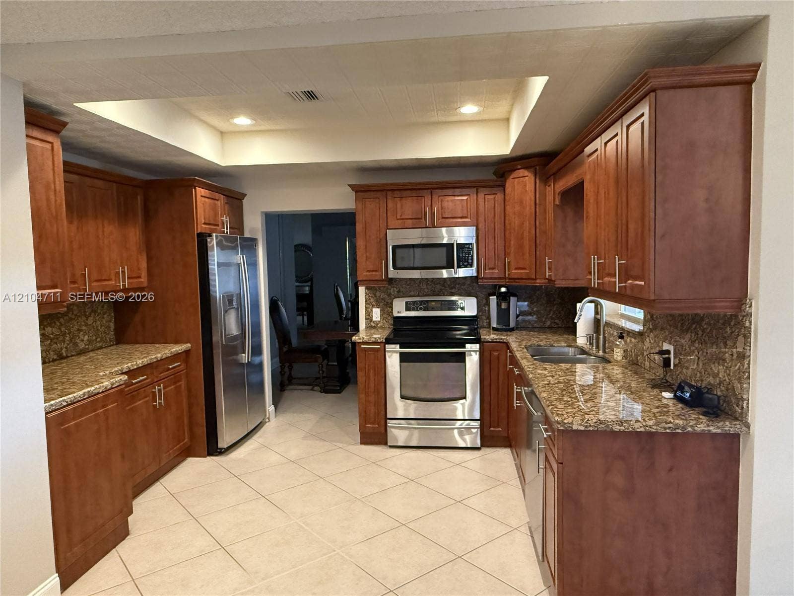 8765 SW 58th Street, Cooper City, FL 33328 Expansive kitchen featuring wood-finish cabinetry, stainless steel appliances, granite countertops, and tile flooring