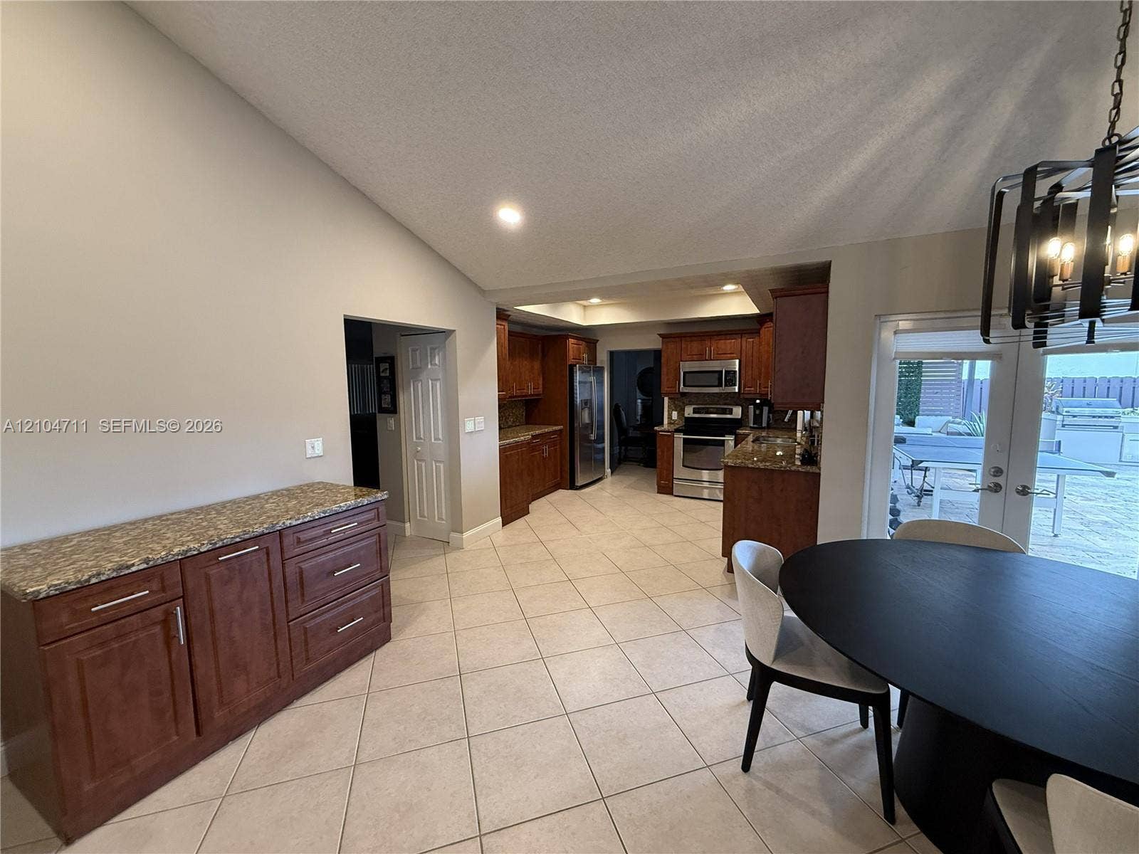 8765 SW 58th Street, Cooper City, FL 33328 Tile flooring throughout, vaulted ceiling, built-in cabinetry with stone countertop, stainless steel appliances, and French doors