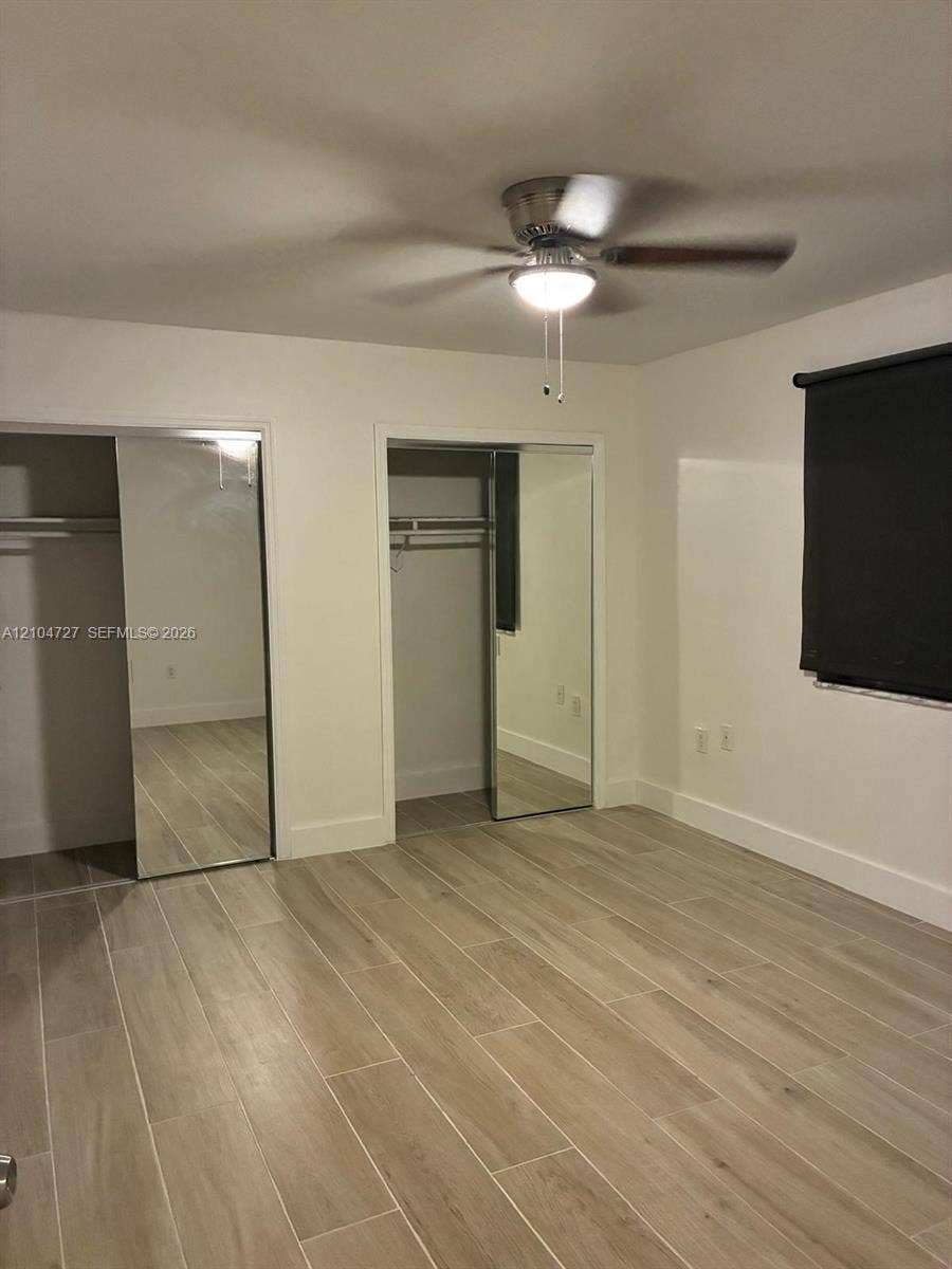 1955 NE 135th Street, #206, North Miami, North Miami, FL 33181 Wood-finish flooring, dual closets with mirrored sliding doors, and a ceiling-mounted light fixture with fan