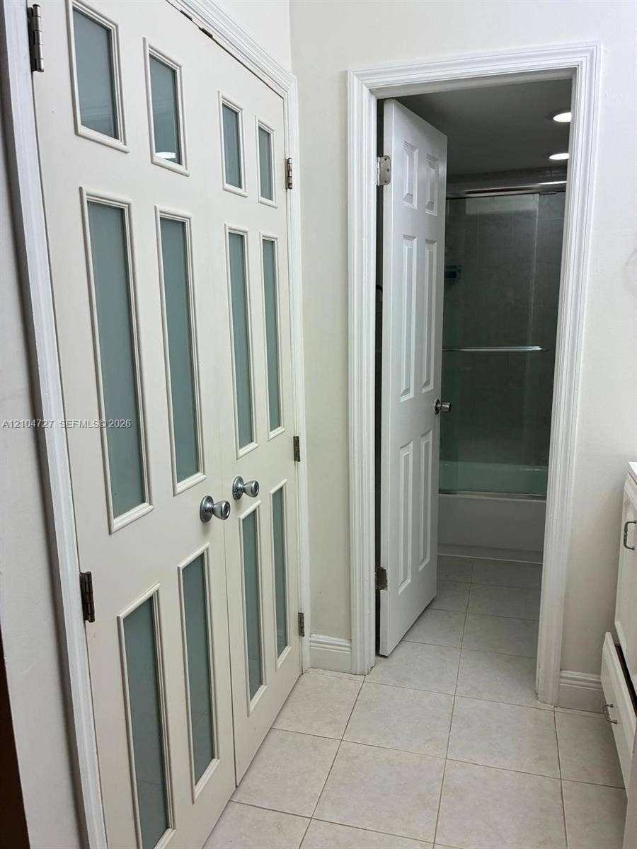 1955 NE 135th Street, #206, North Miami, North Miami, FL 33181 Double-panel doors featuring frosted glass inserts and chrome hardware, paired with a six-panel door opening to a tub and shower combination with tile flooring