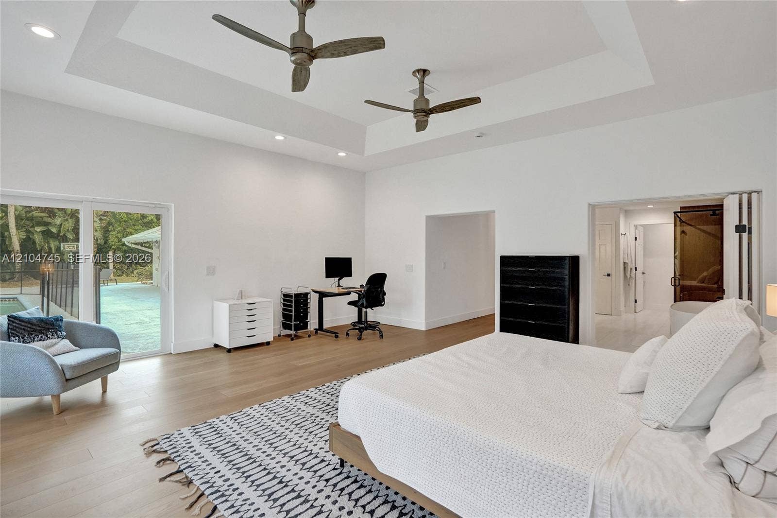 Recessed lighting, tray ceiling, two ceiling fans, wood-finish flooring, and sliding glass doors to the exterior