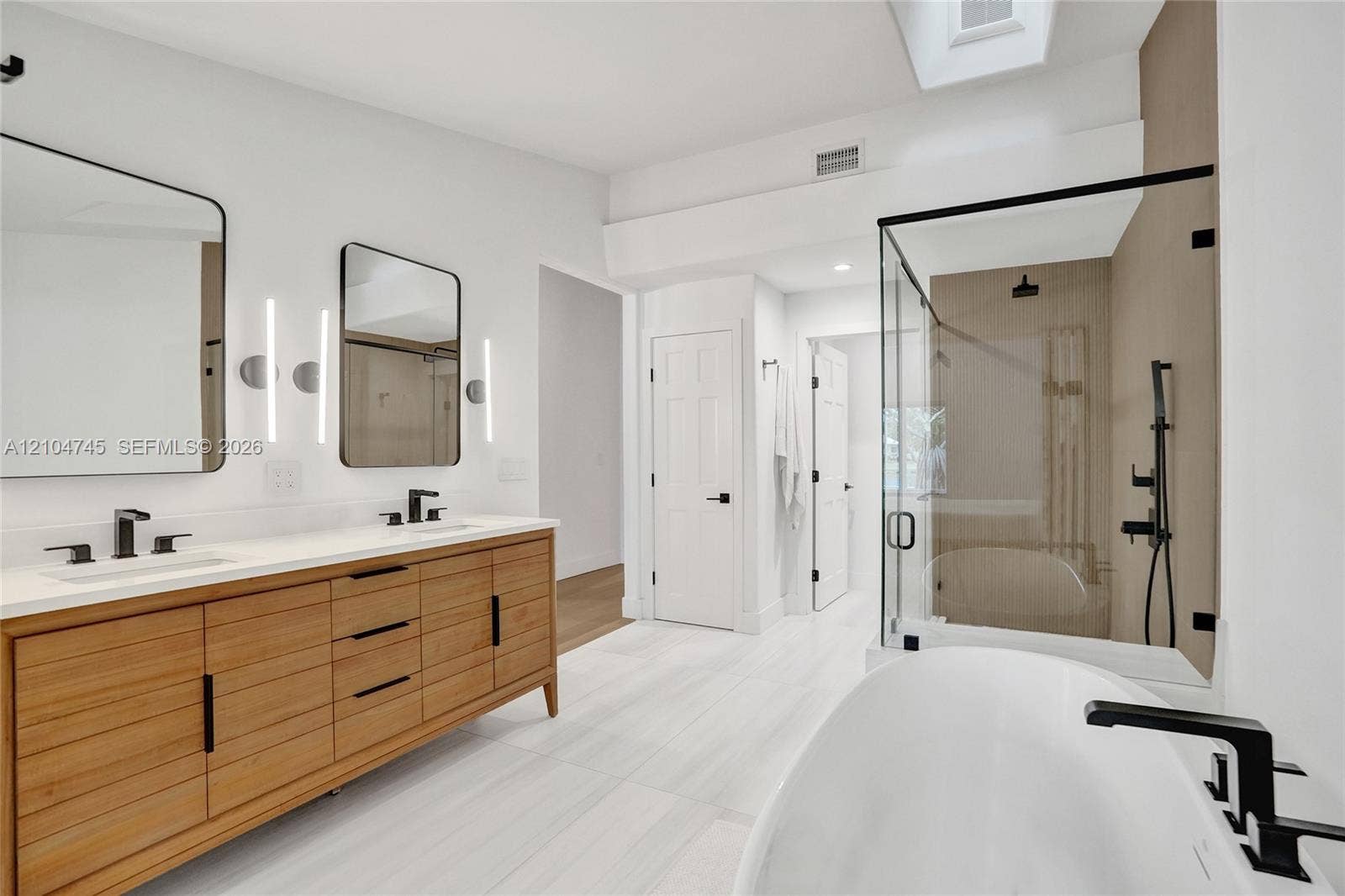 Dual vanity with wood-finish cabinetry, white countertop, and matte black fixtures
