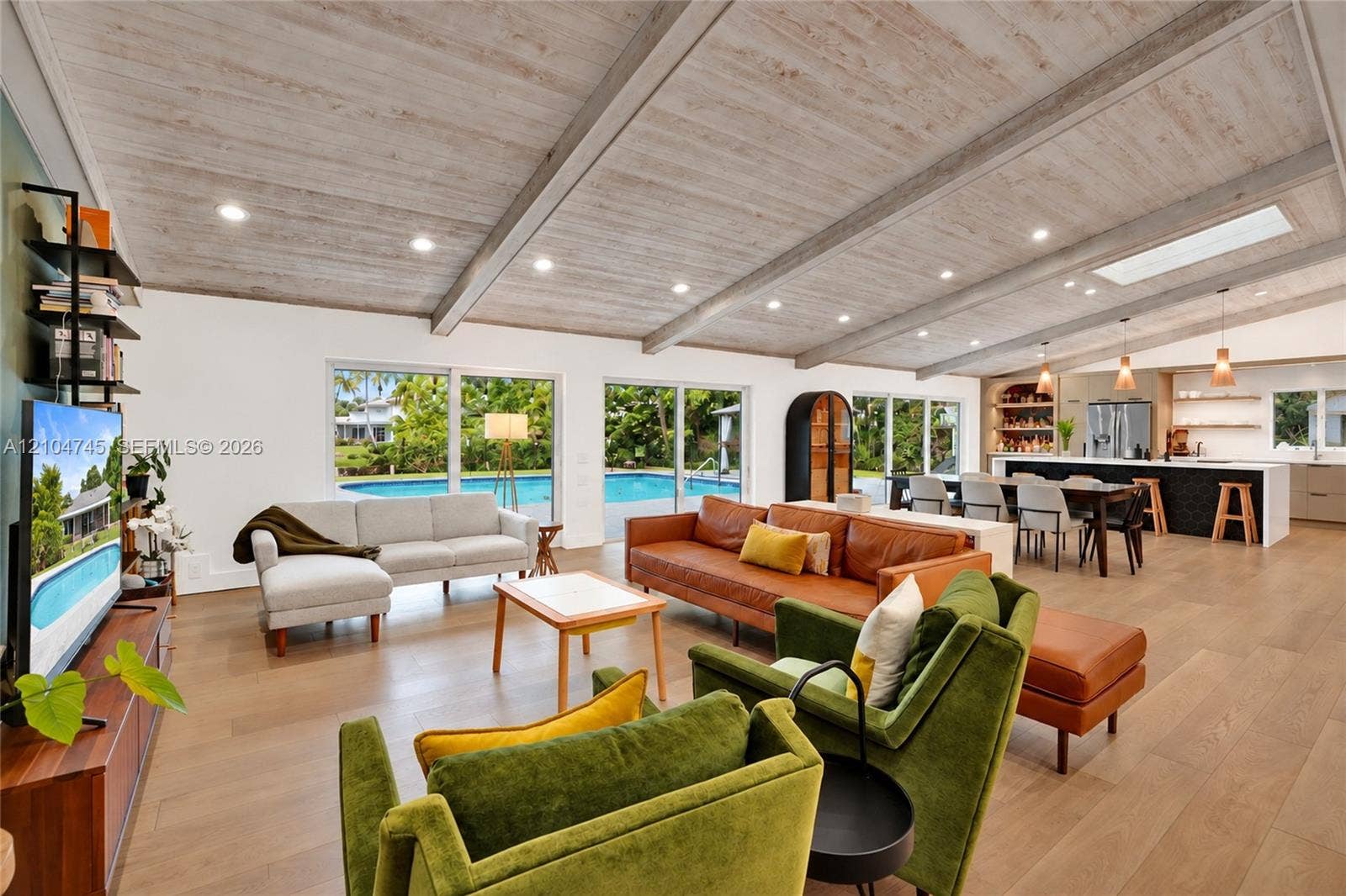 Vaulted wood-finish ceiling with exposed beams, wood-finish flooring, sliding glass doors, recessed lighting, and a skylight
