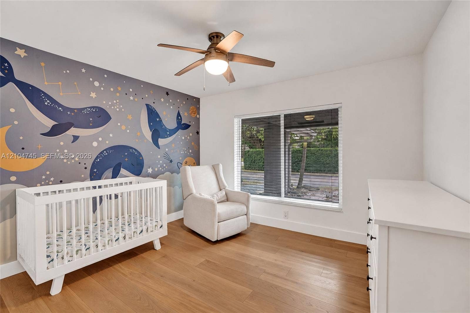 Wood-finish flooring, ceiling fan with integrated lighting, and a large window with blinds