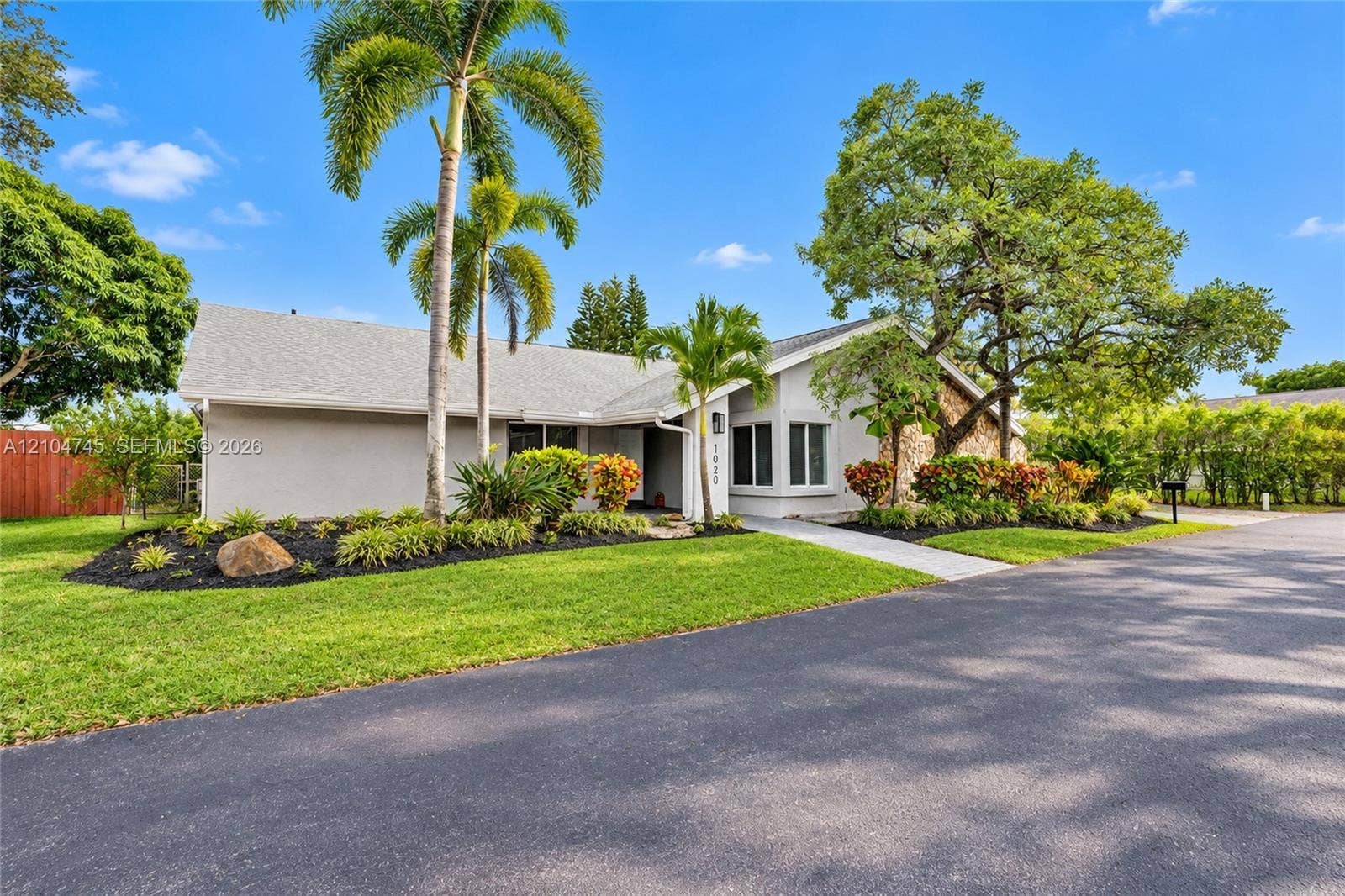 Stucco exterior with stone accents, mature trees, and landscaped grounds