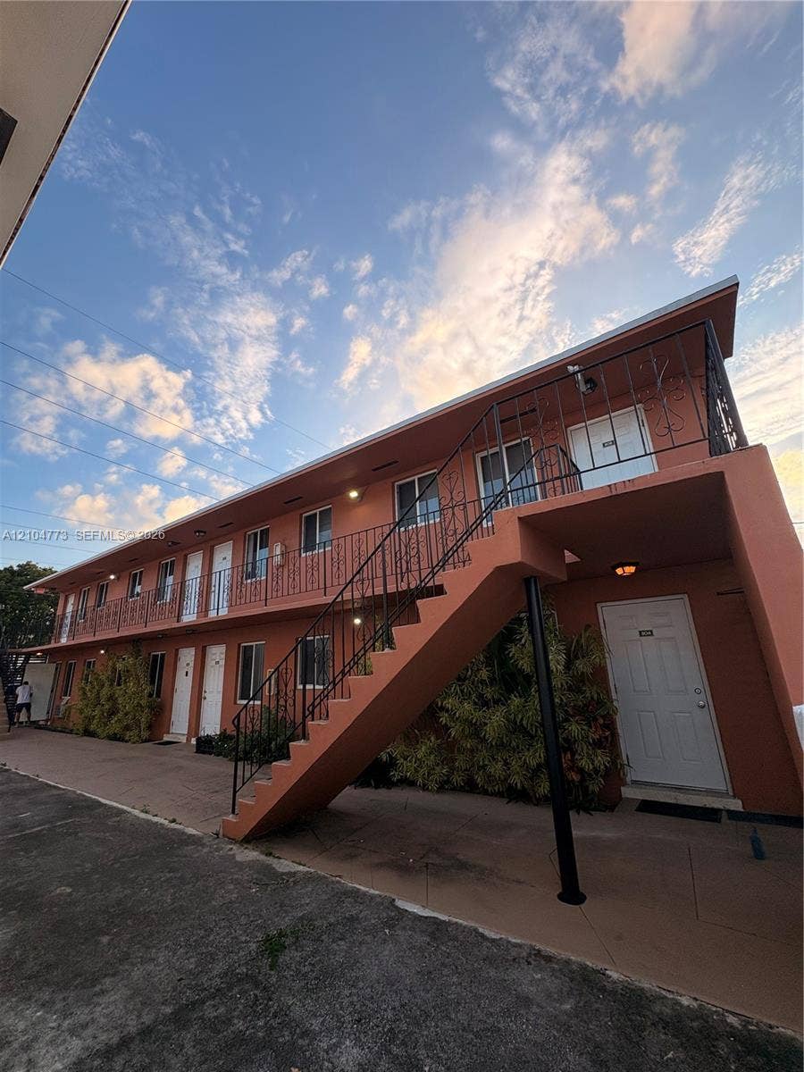 Two-story building with a stucco exterior, multiple entry doors, and an exterior staircase with metal railings