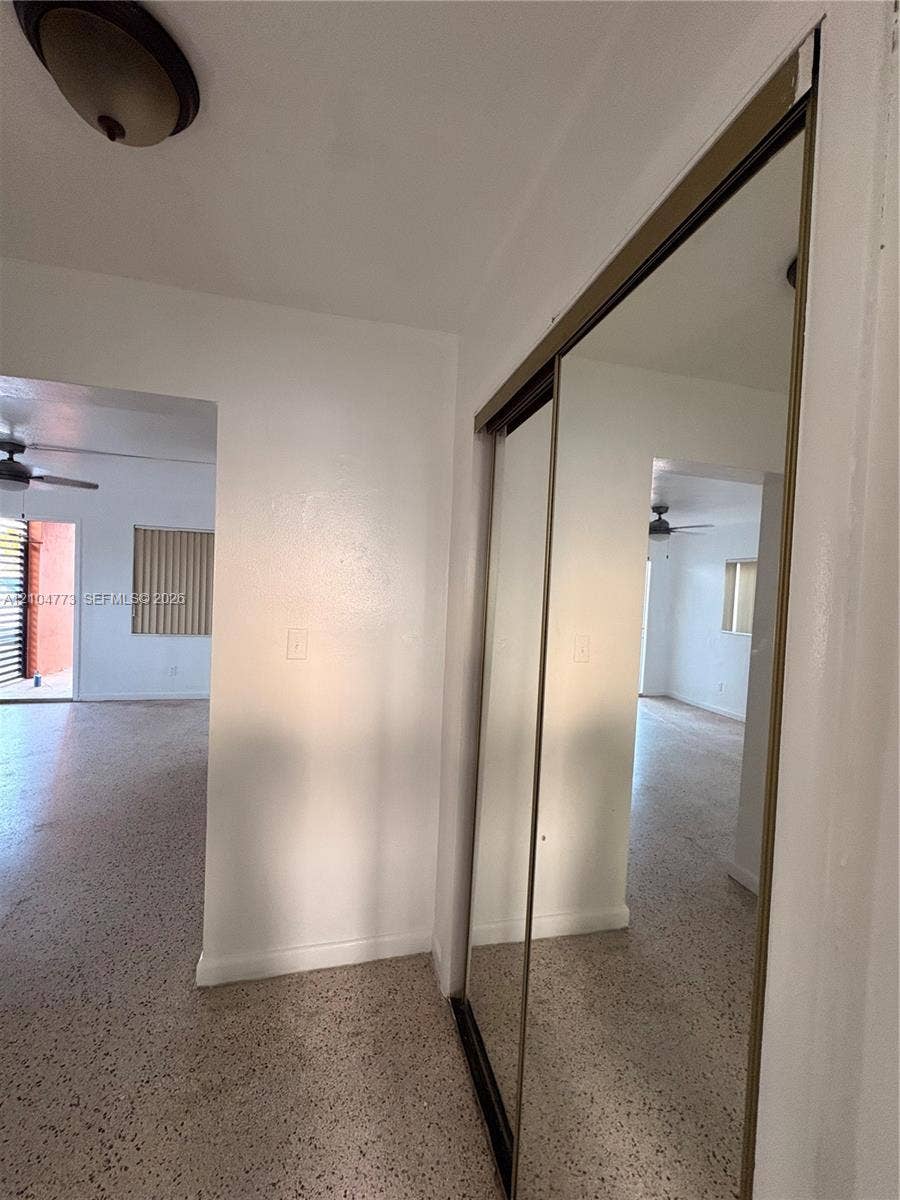 Mirrored sliding closet doors, ceiling-mounted light fixture, and terrazzo flooring