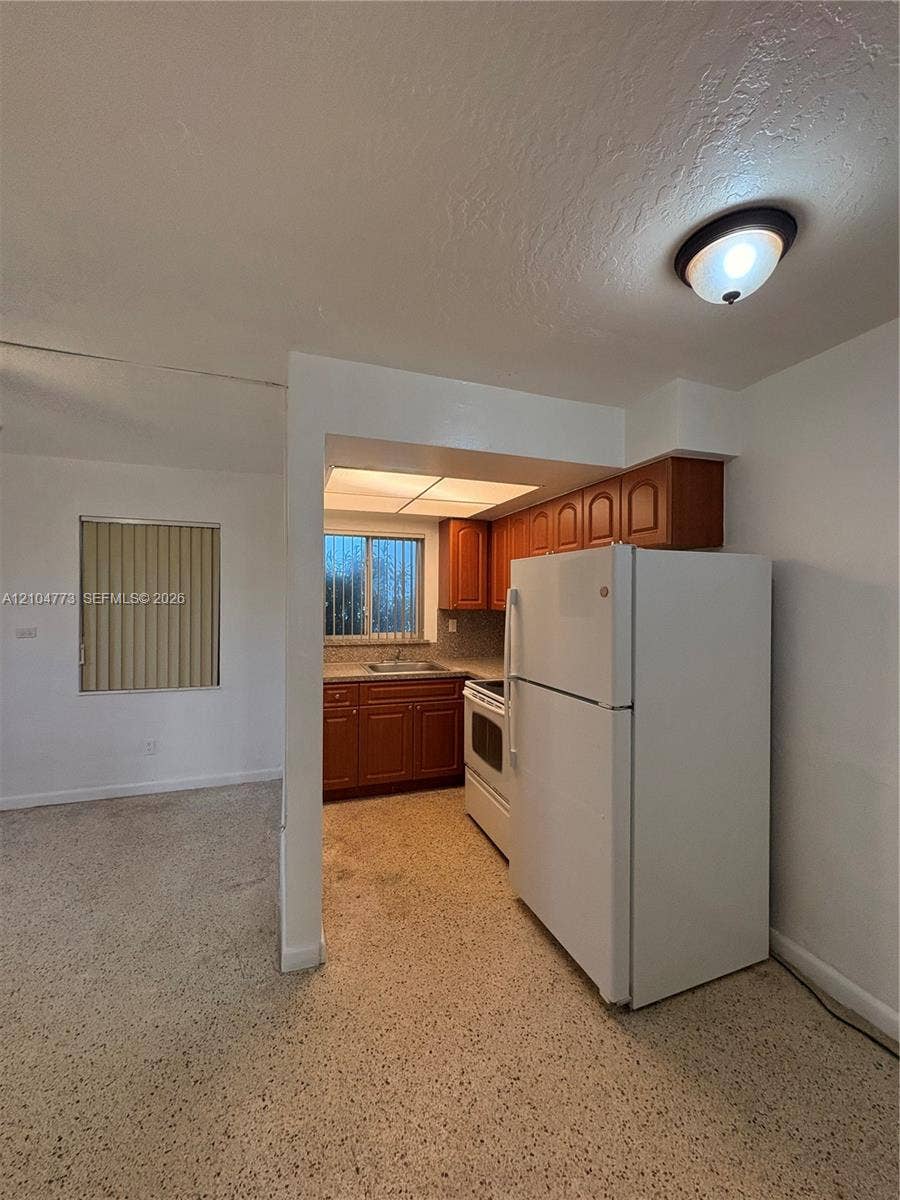 Kitchen featuring wood-finish cabinetry, a freestanding refrigerator, and a built-in range