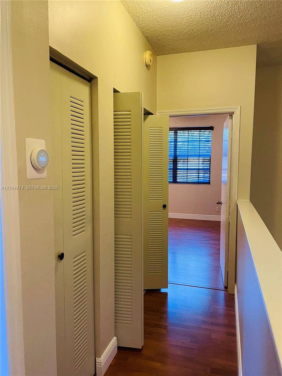 1503 Veracruz Lane, #5-14, Weston, Weston, FL 33327 Hallway featuring wood-finish flooring, dual bi-fold louvered closet doors, and a smart thermostat