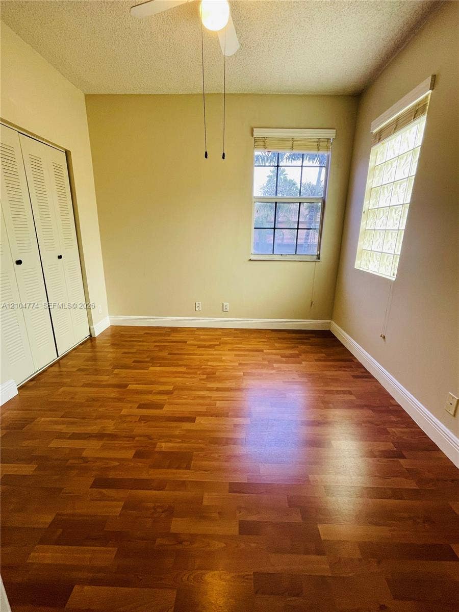 1503 Veracruz Lane, #5-14, Weston, Weston, FL 33327 Room featuring wood-finish flooring, a glass block window, a dual-panel window with muntins, and built-in closet storage with louvered doors