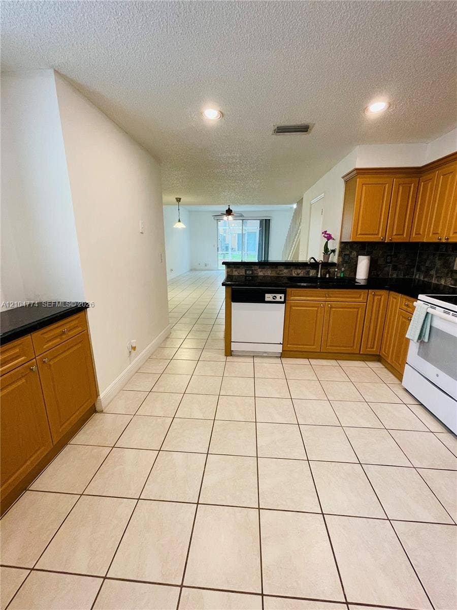 1503 Veracruz Lane, #5-14, Weston, Weston, FL 33327 Kitchen featuring wood cabinetry, dark stone-finish countertops, ceramic tile flooring, and recessed ceiling lighting