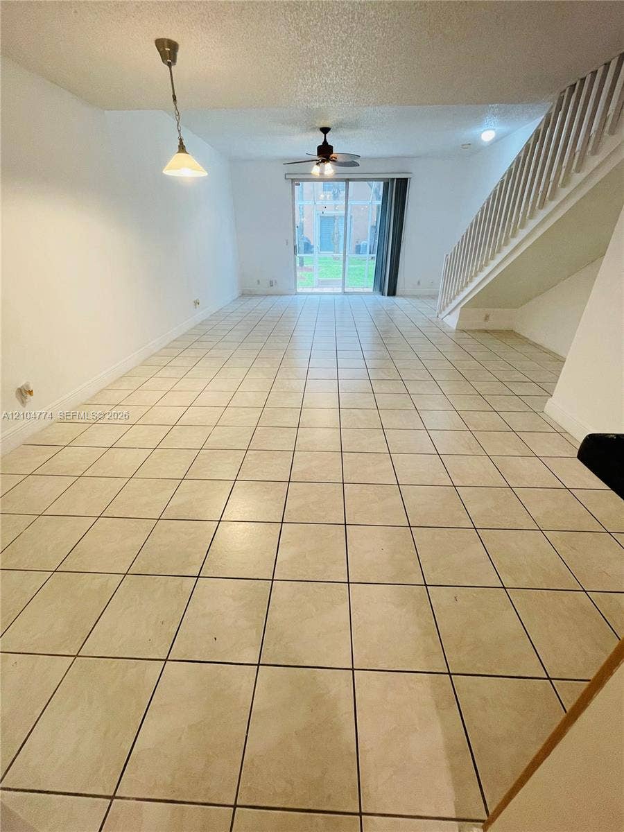 1503 Veracruz Lane, #5-14, Weston, Weston, FL 33327 Open-concept room featuring neutral ceramic tile flooring, a staircase with a wooden balustrade, a ceiling fan, and sliding glass doors