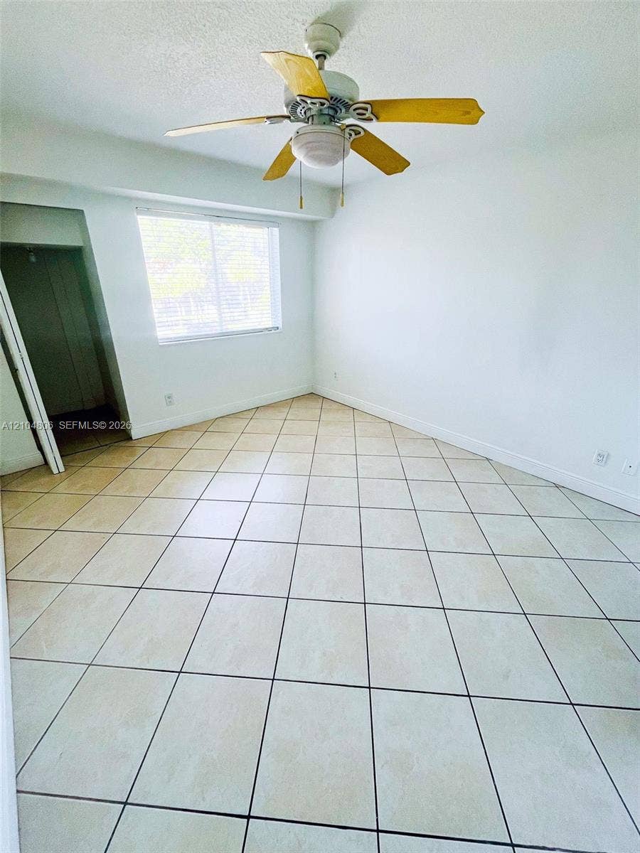 10451 SW 157th Place, #303, Miami, FL 33196 Room featuring tile flooring, white walls, a window with blinds, and a ceiling fan with light fixture