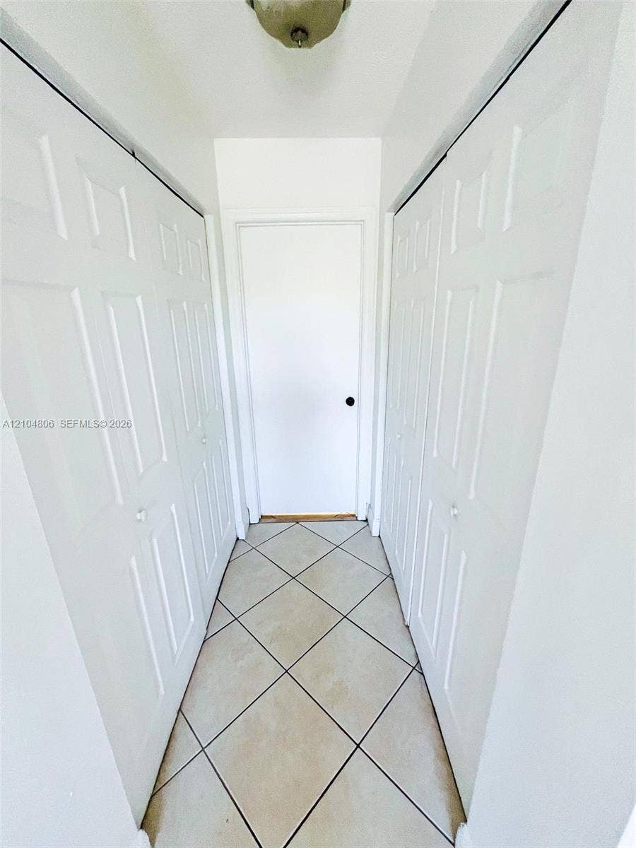 10451 SW 157th Place, #303, Miami, FL 33196 Hallway featuring ceramic tile flooring, bi-fold closet doors, and a flush mount ceiling light fixture