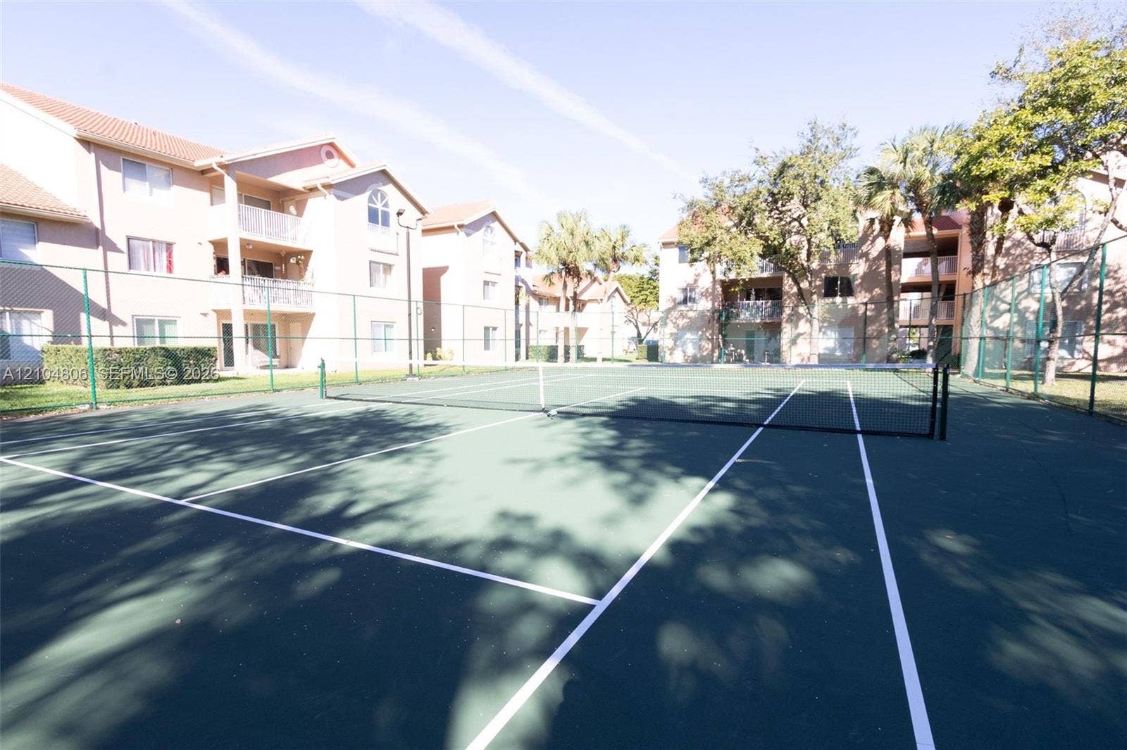 10451 SW 157th Place, #303, Miami, FL 33196 Tennis court with dark green surfacing and white lines, surrounded by fencing