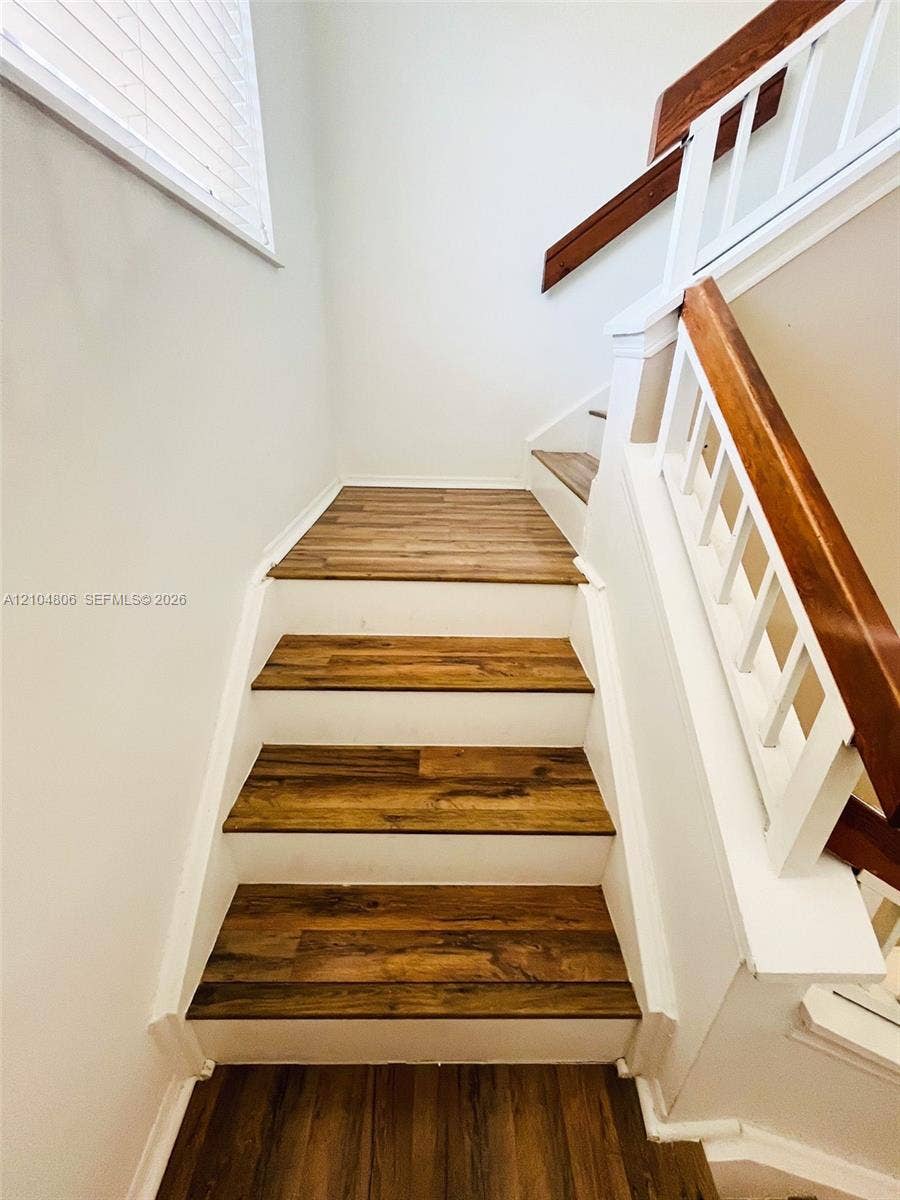 10451 SW 157th Place, #303, Miami, FL 33196 Staircase featuring wood-finish treads, white risers, and a matching handrail with white balusters