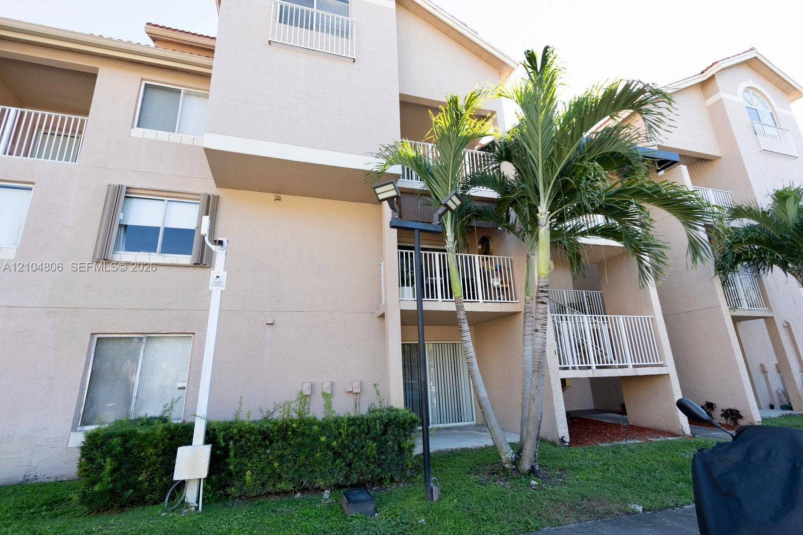 10451 SW 157th Place, #303, Miami, FL 33196 Multi-story building exterior with individual balconies, architectural roofline, and established palm trees