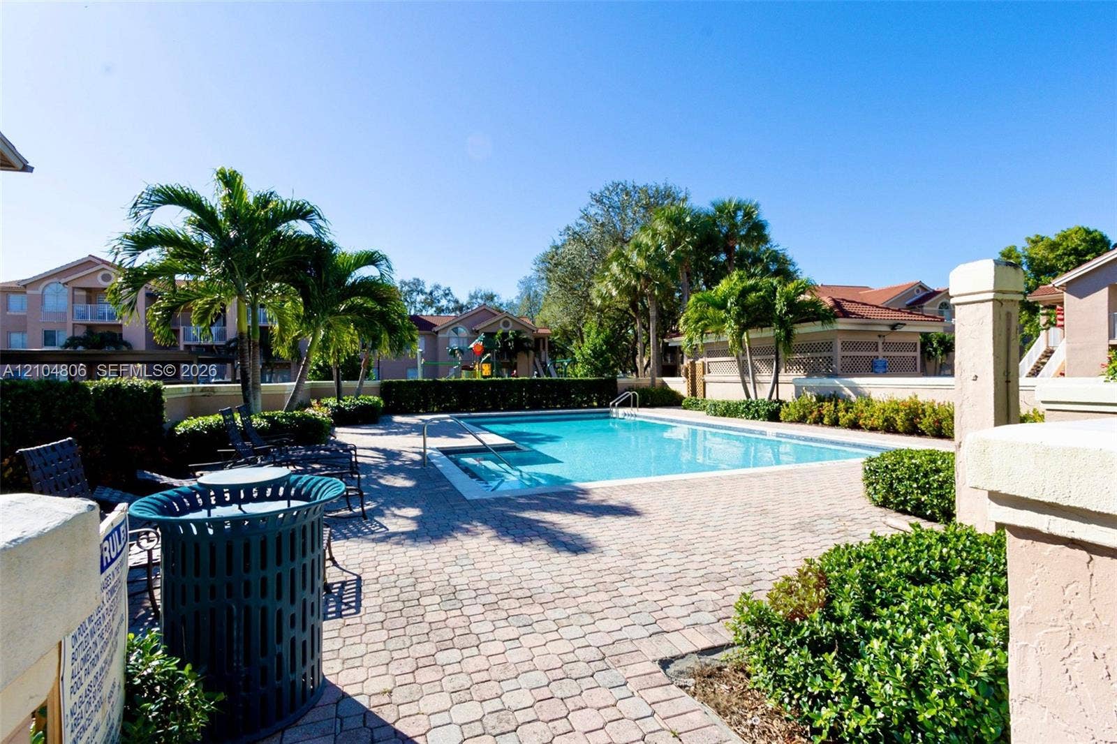 10451 SW 157th Place, #303, Miami, FL 33196 Expansive outdoor pool with integrated steps, surrounded by paver decking and mature palm trees