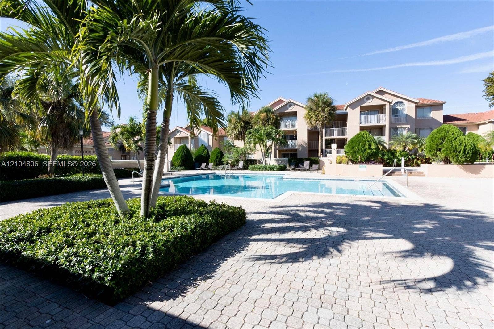 10451 SW 157th Place, #303, Miami, FL 33196 Community swimming pool with a paved deck, surrounded by mature palm trees and landscaped shrubbery