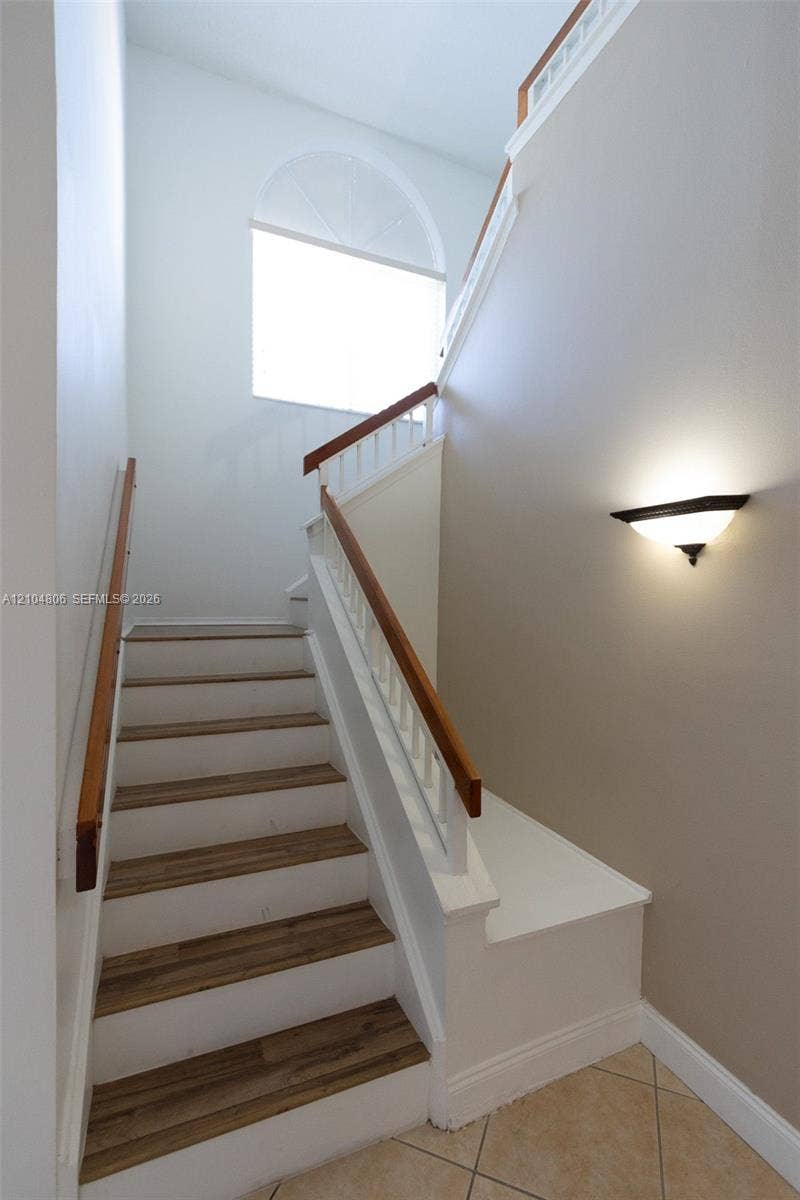 10451 SW 157th Place, #303, Miami, FL 33196 Staircase featuring wood-finish treads, white risers, and a wood handrail